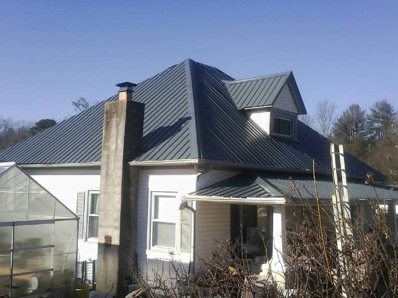 Dark blue standing seam metal roof on a white farmhouse with dormer — Slate & Tile Roof Repair by Roofing Brothers in Layton