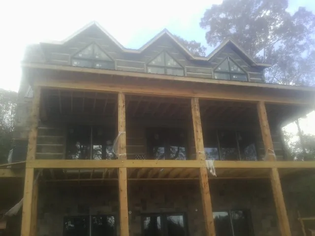 Dormers and porch framing on a large log home under construction — Roof Coating work by our crew in Layton