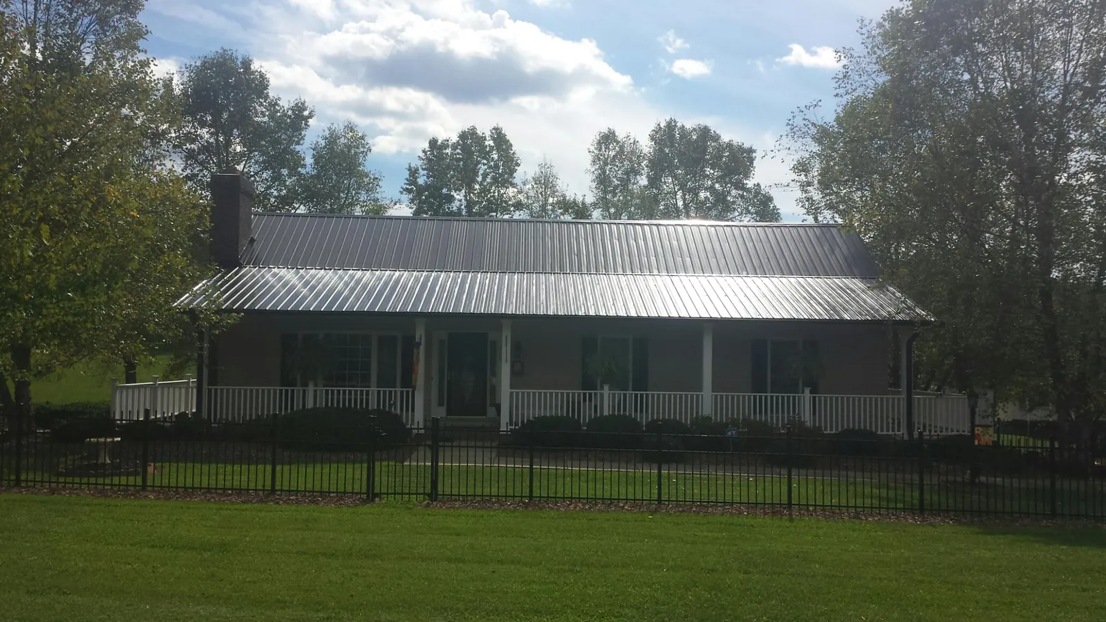 Gray metal roof on a brick ranch with a full width front porch — Gutter Guard Installation work by our crew in Layton