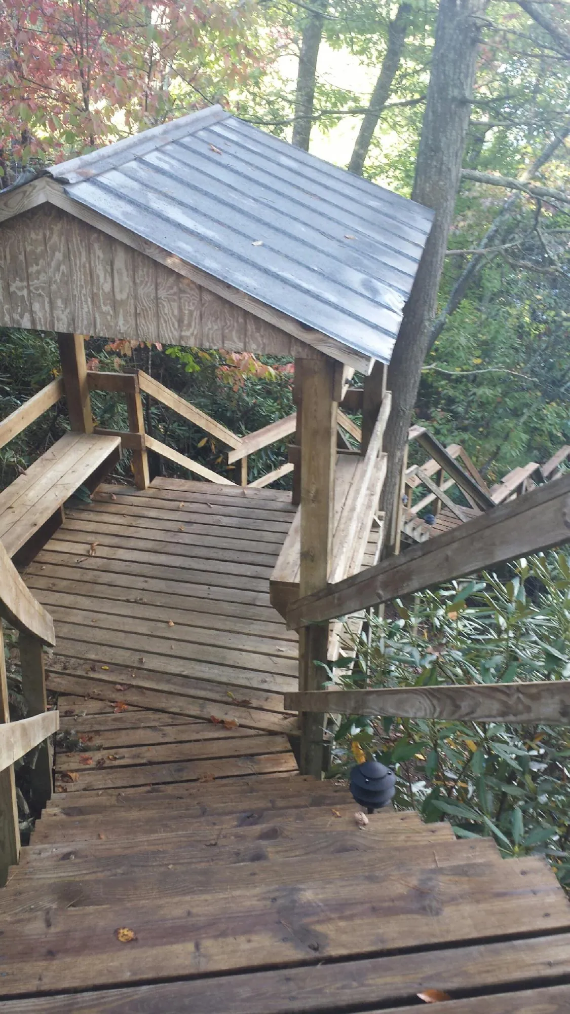 Metal roofed shelter over wooden steps on a wooded walkway — Skylight Repair & Installation work by our crew in Layton